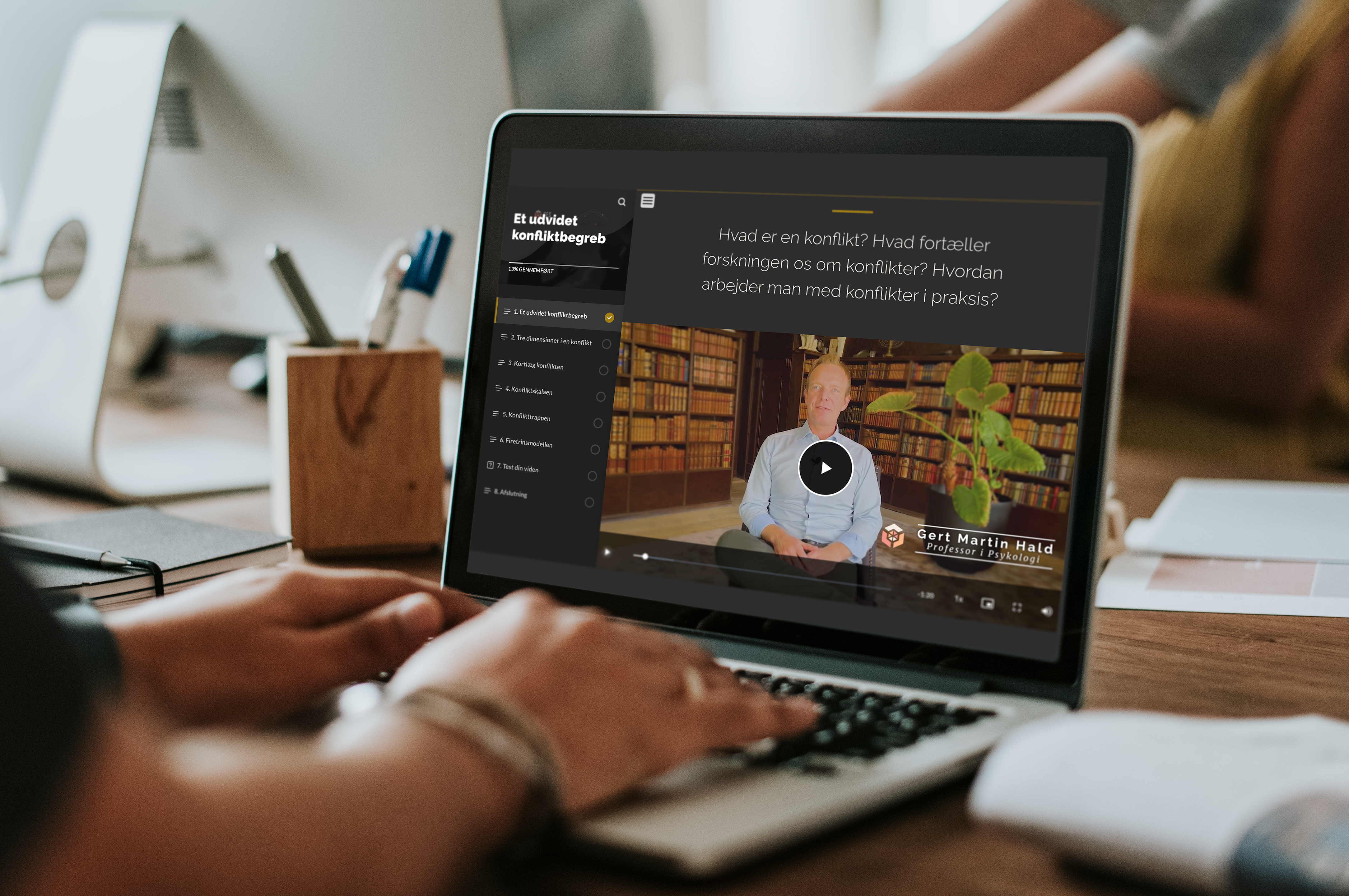 A person sitting at a table reviews the SES website video on a laptop