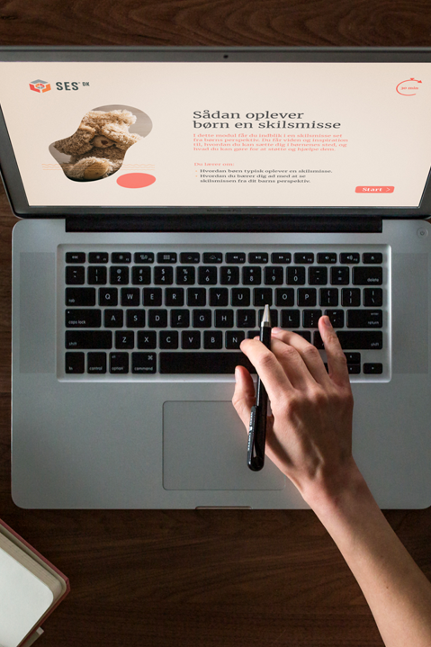 Top down view of a right hand navigating a laptop keyboard, while the left holds open a calendar book