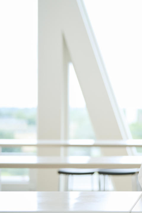 A blonde woman in a white shirt sits at a table with hands folded