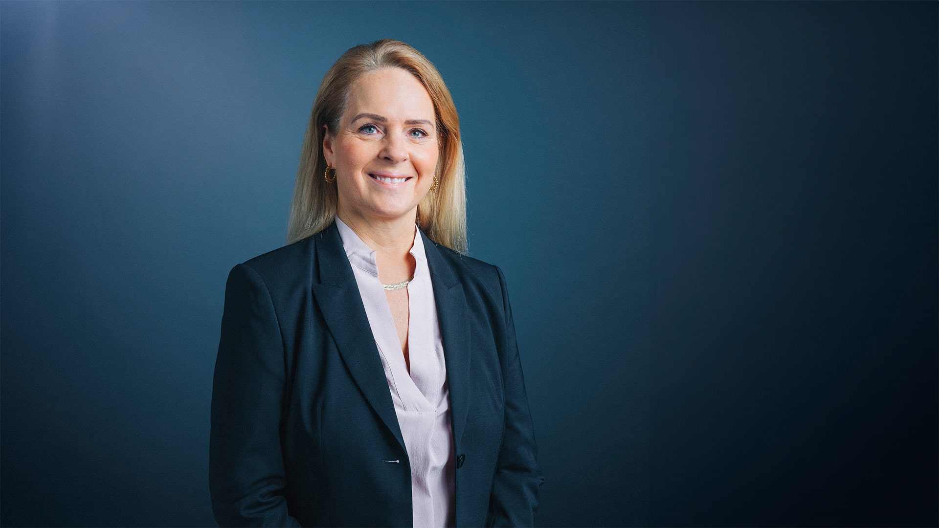 A woman in a suit smiles and poses for a professional photo