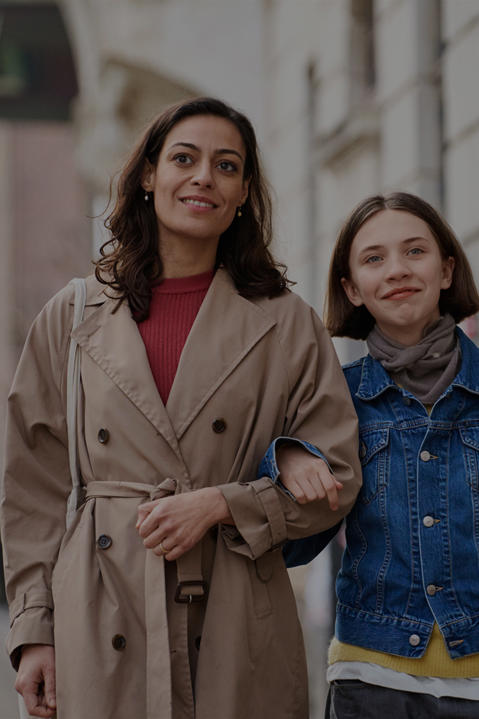 Woman and child walking down a street with interlocked arms, with a phone showing the SES website in the foreground